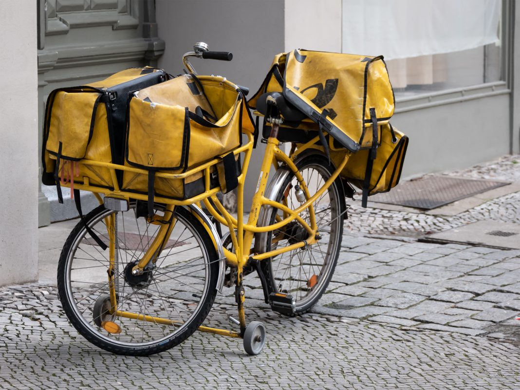 Black And Yellow Bicycle of German Deutsche Post On The Sidewalk In Berlin
